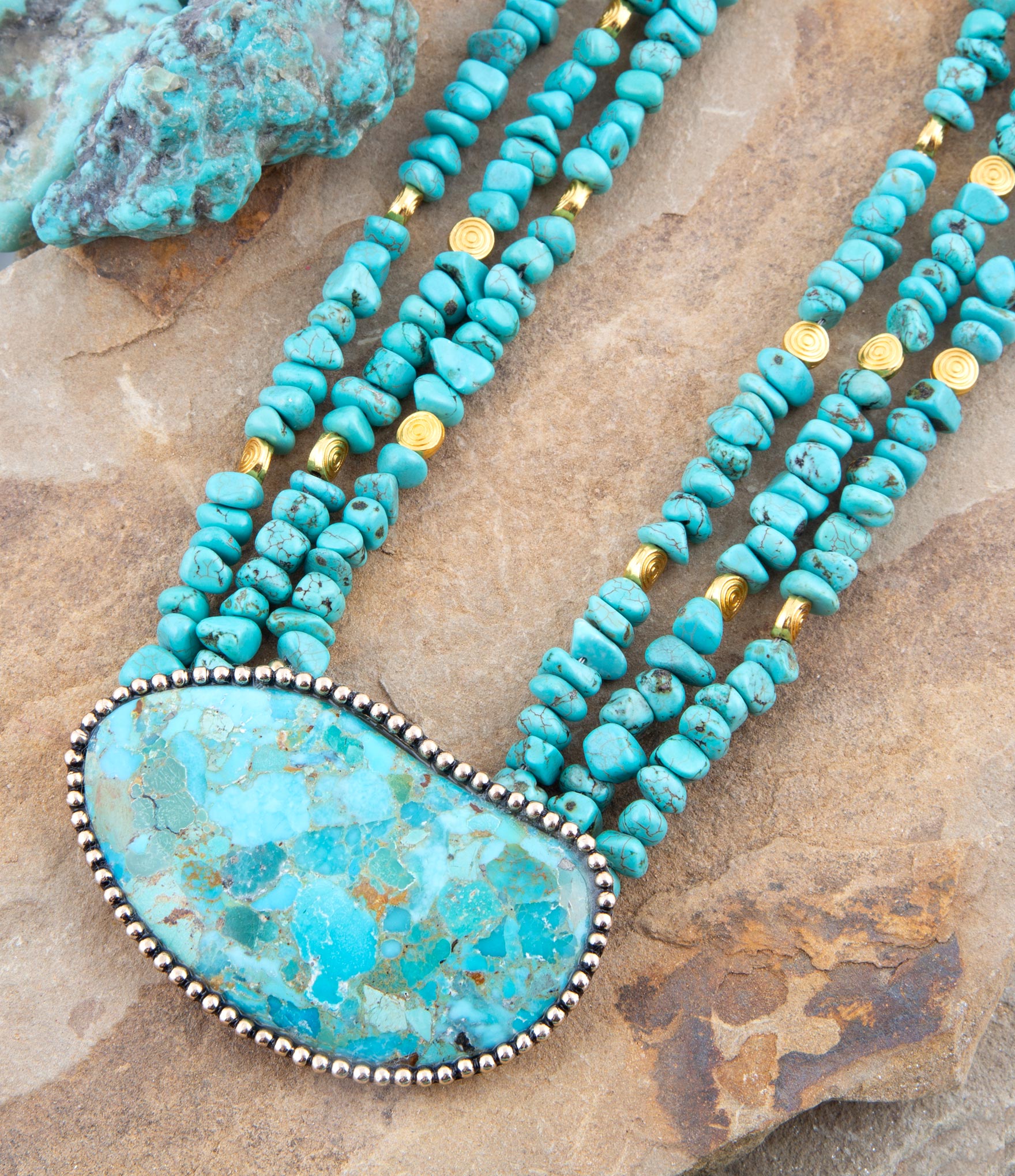 Turquoise beaded statement necklace with large turquoise stone pendant and gold accents.